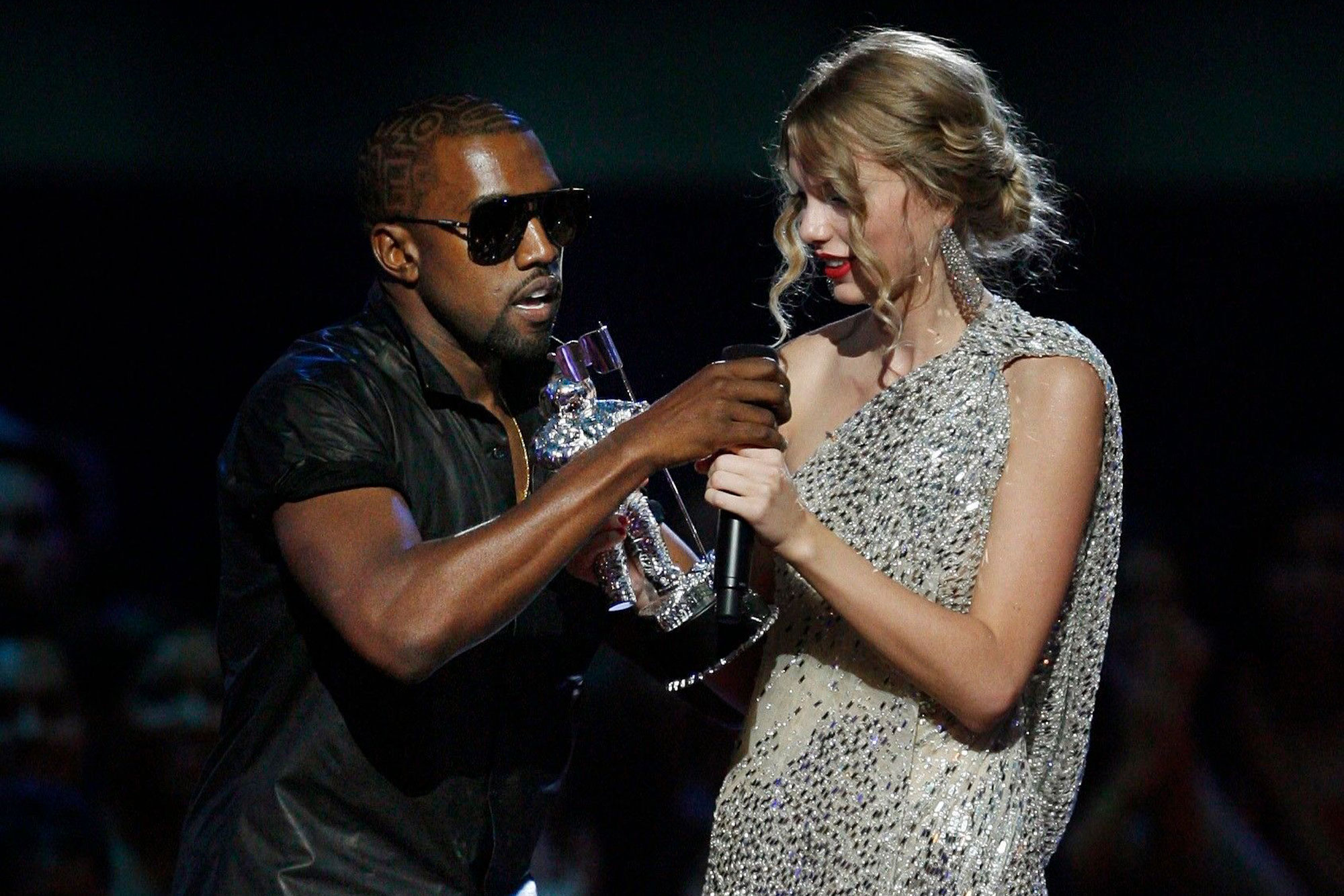 Taylor Swift leaves the stage while handing the mic to Kanye West.