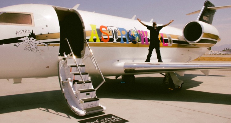 Travis Scott standing atop his private jet